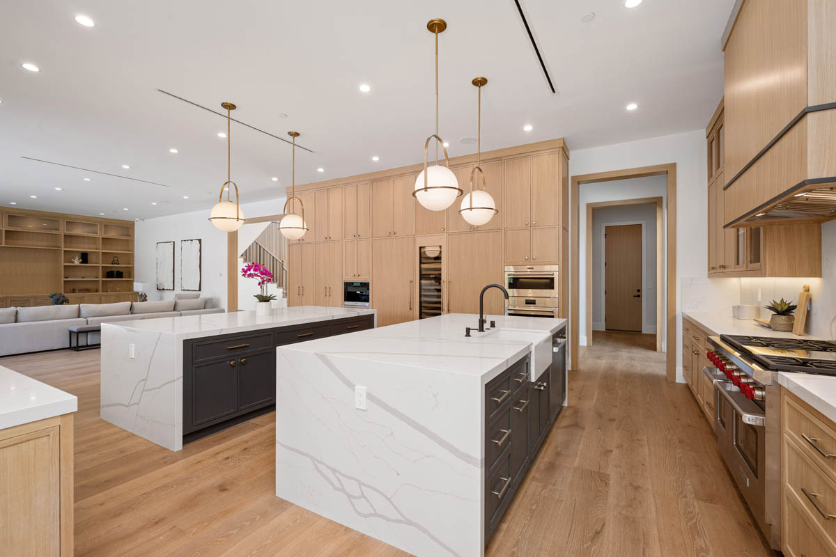 Spacious remodeled kitchen with light wood cabinetry, two islands, and pendant lighting