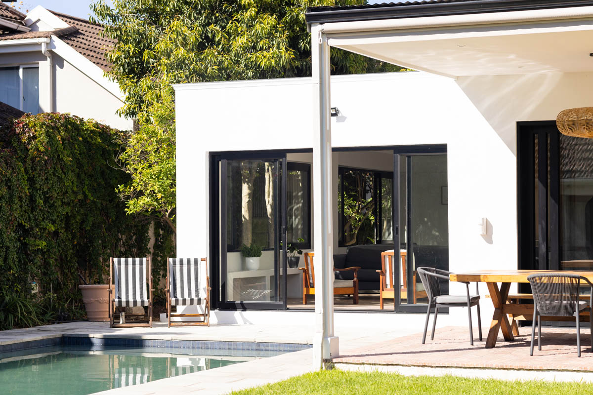 Modern white home renovation opening onto a poolside patio